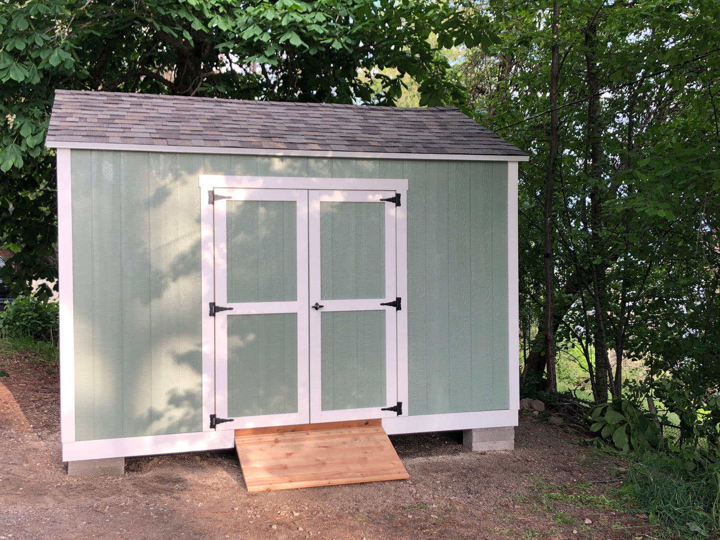 Custom teal shed with white trim and ramp.