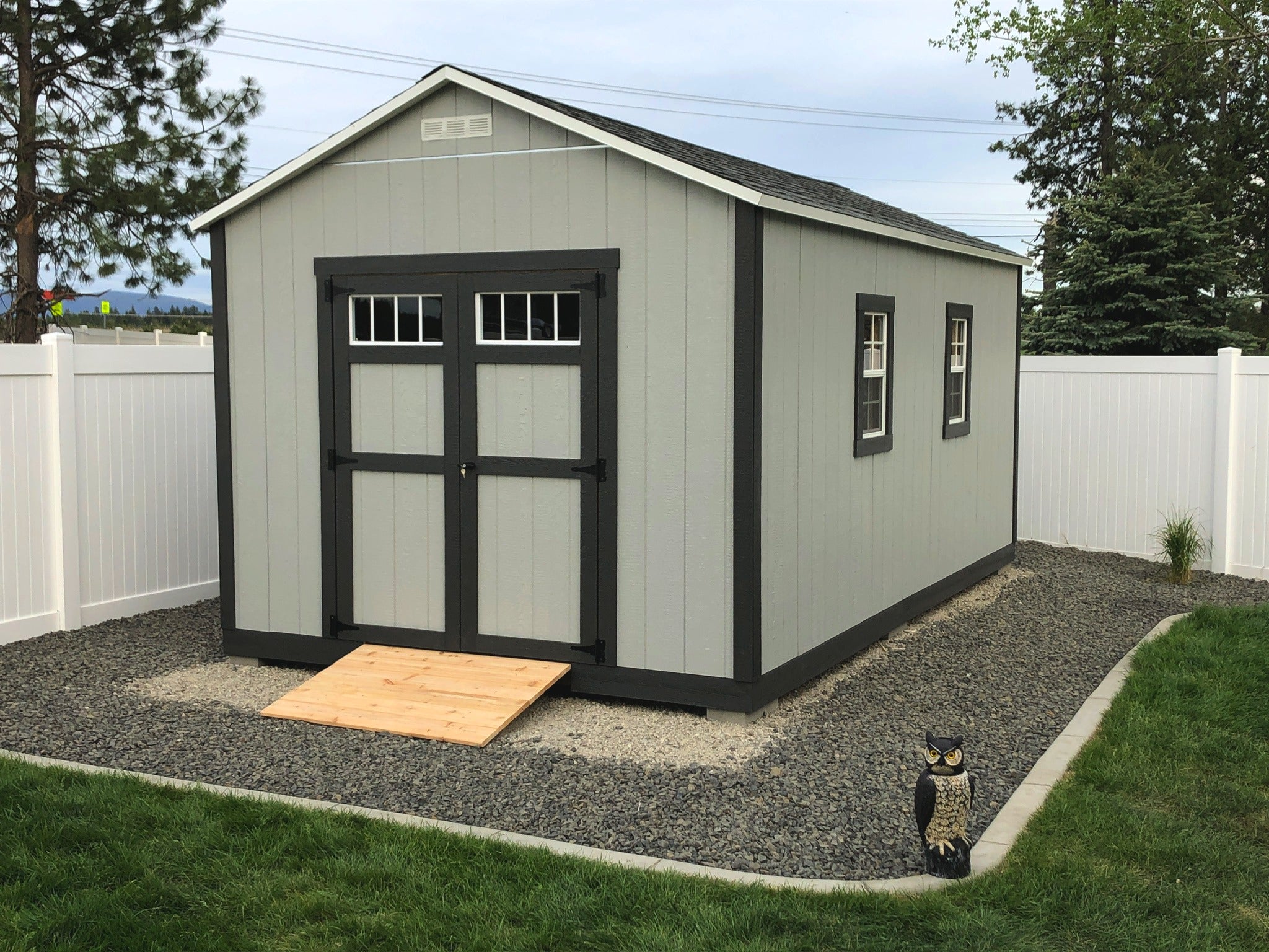 Grey custom shed with black trim and two windows.